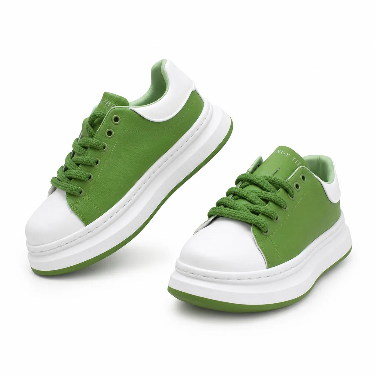 A pair of green and white platform sneakers with matching green laces, shown on a clean white background.