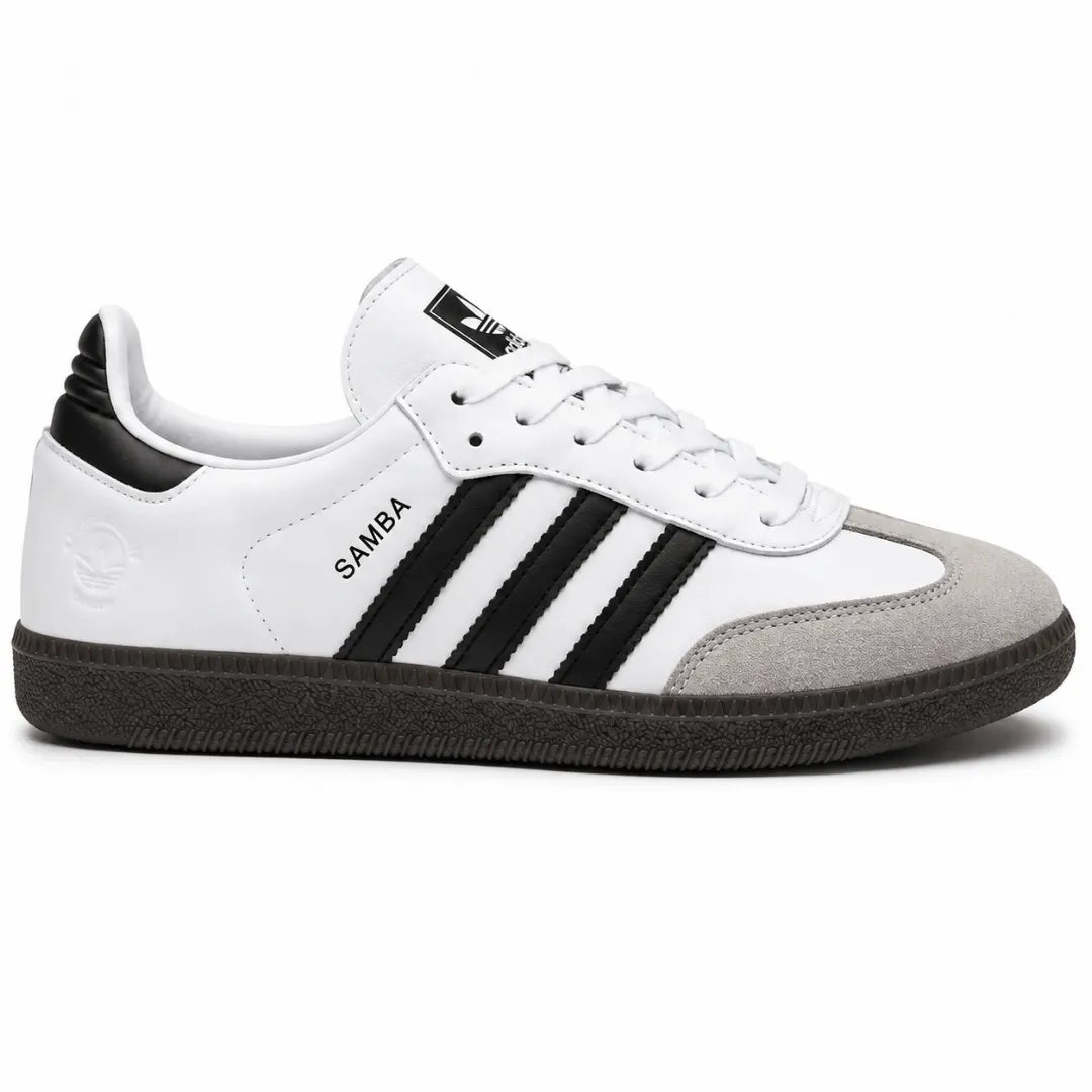 A classic Adidas Samba sneaker in white, black, and gray, featuring the signature three stripes on the side, white laces, and a dark gray sole, shown against a plain white background.