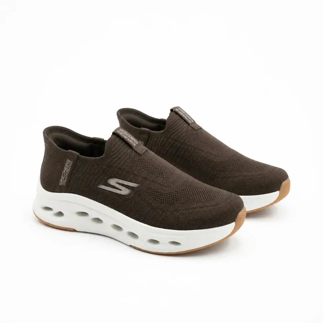 A pair of dark brown Skechers slip-on athletic sneakers with a white cushioned sole and gum outsole, displayed on a clean white background.