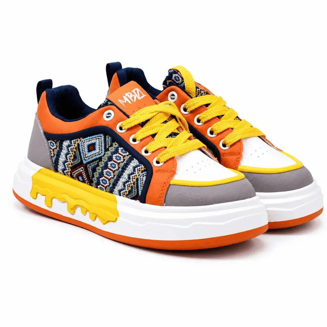 A pair of low-top sneakers with a vibrant color scheme. The shoes feature orange overlays, white toe caps, gray midsoles, yellow laces and a yellow dripping sole accent, and a navy blue side panel with a colorful geometric pattern.
