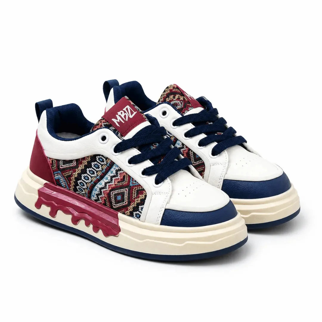A pair of low-top sneakers on a white background. The shoes feature a white leather upper with navy blue accents, a navy blue lace, and a side panel with a colorful geometric pattern.