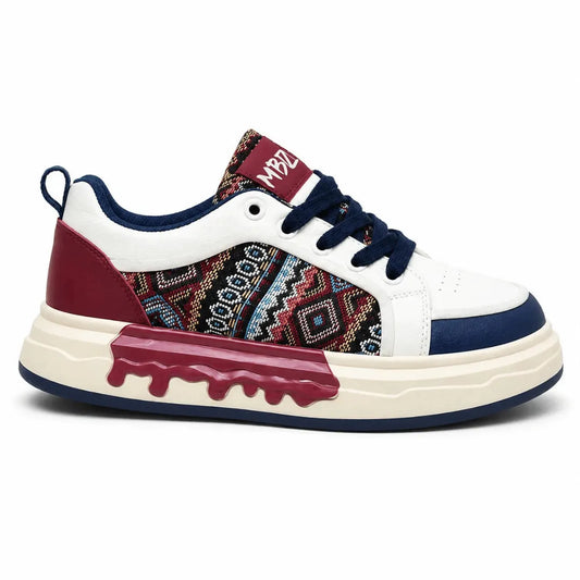 A low-top sneaker with a white leather upper, navy blue laces and collar, a burgundy heel counter, and a multicolor geometric patterned side panel. It features a thick cream platform sole with a burgundy dripping design on the front.