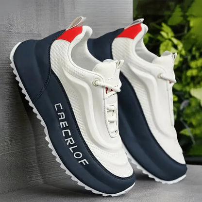 A pair of chunky platform sneakers in off-white and navy blue, featuring a red accent at the heel and the brand name 'CABRLOF' printed vertically on the side, set against a gray textured wall with green foliage in the background.