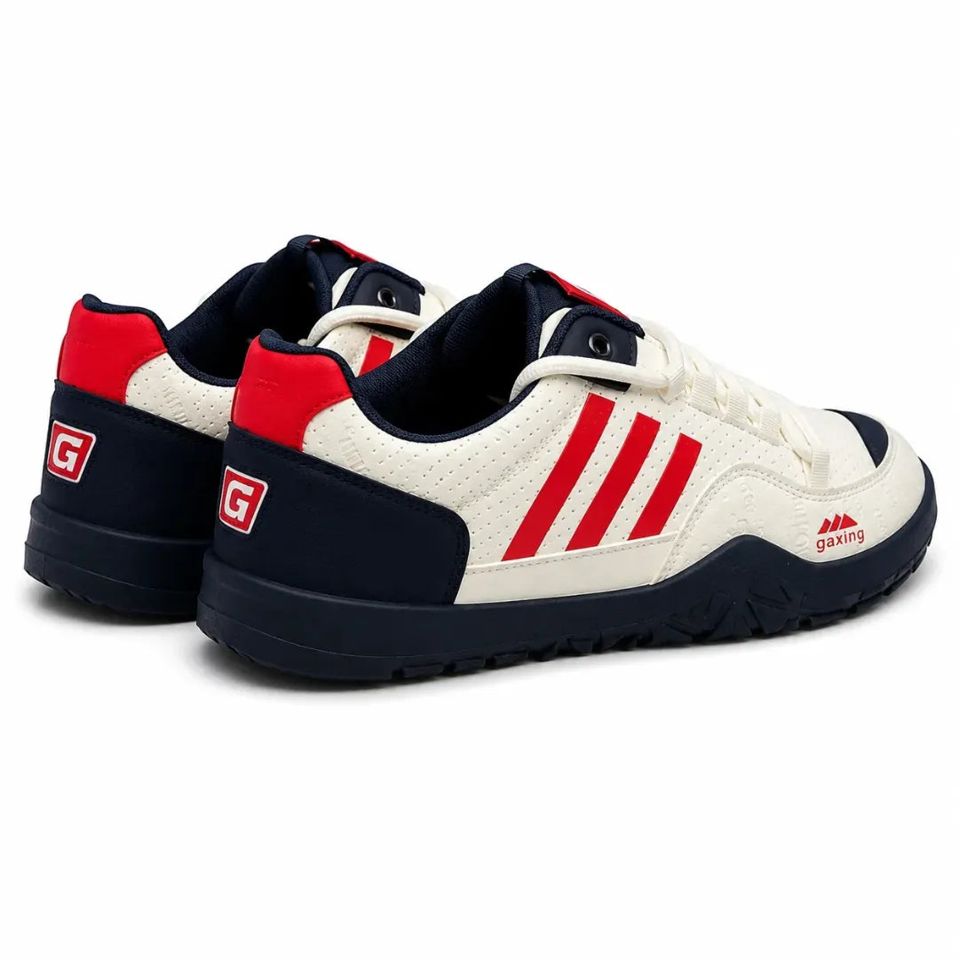 A pair of low-top sneakers in off-white, navy blue, and red. The off-white leather upper features three red stripes on the side, a red heel tab, and a red logo on the midfoot, while the collar, lining, and outsole are navy blue.
