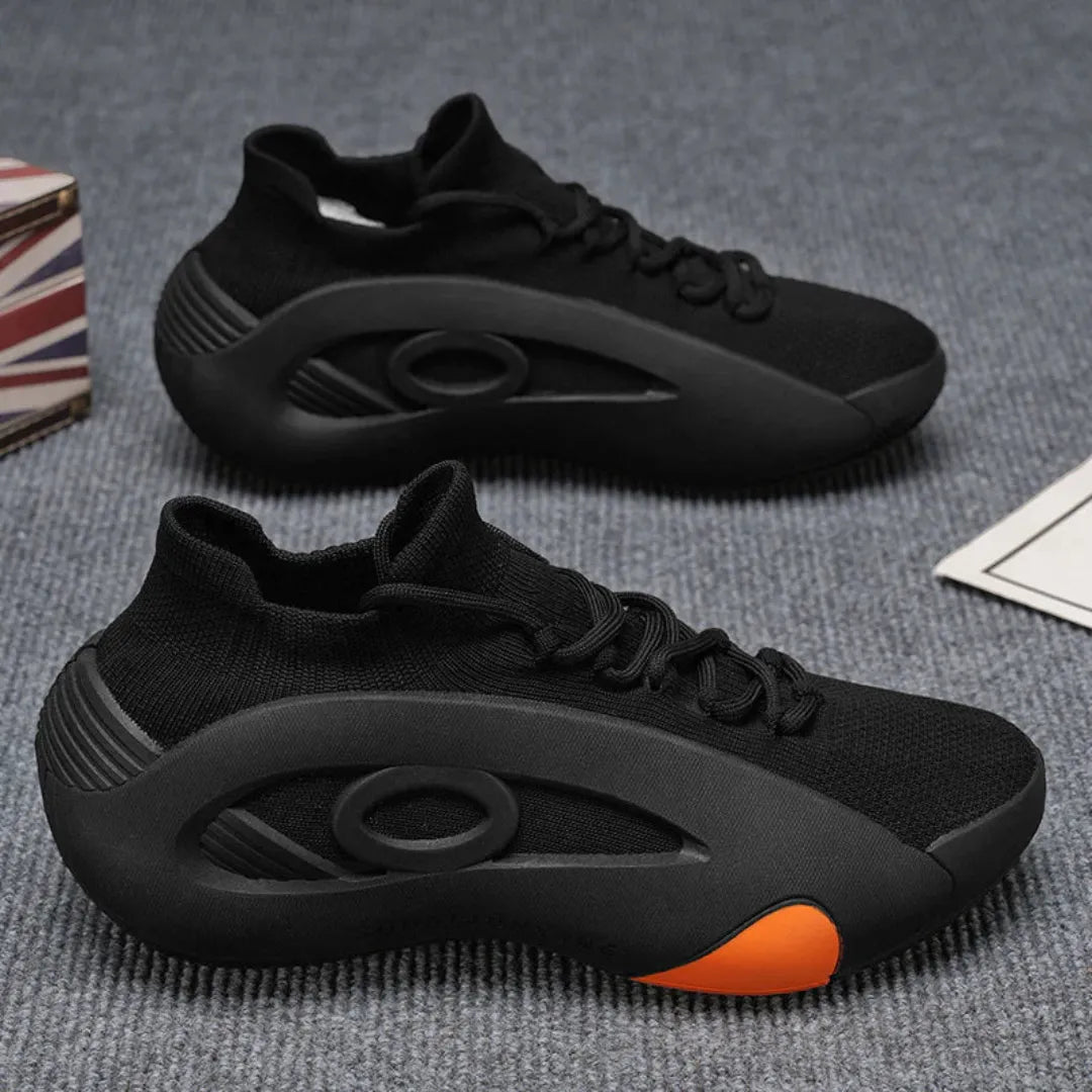 Black athletic shoes with orange accents on a textured surface