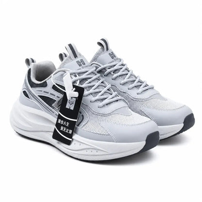 A pair of light gray and white athletic sneakers with black accents, featuring a chunky sole and a black hangtag with Chinese text, set against a plain white background.