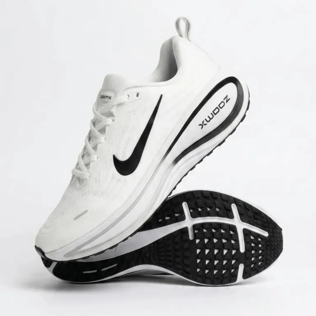 A white Nike running shoe with a black Swoosh and black outsole, shown from a high angle with the second shoe flipped to display the black tread pattern on a light gray background.