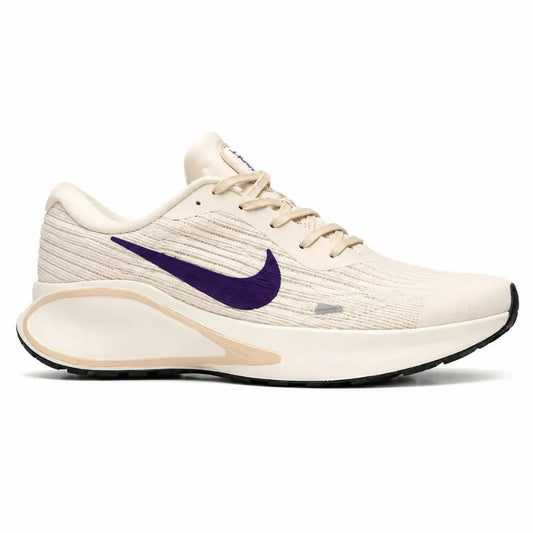 A Nike running shoe in cream and purple, featuring a textured knit upper, a large purple Swoosh, and a chunky cream midsole with a black outsole, shown against a plain white background.
