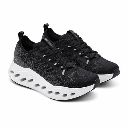 A pair of black athletic sneakers with a textured knit upper, black laces, and a thick white cushioned sole with circular cutouts, shown on a white background.