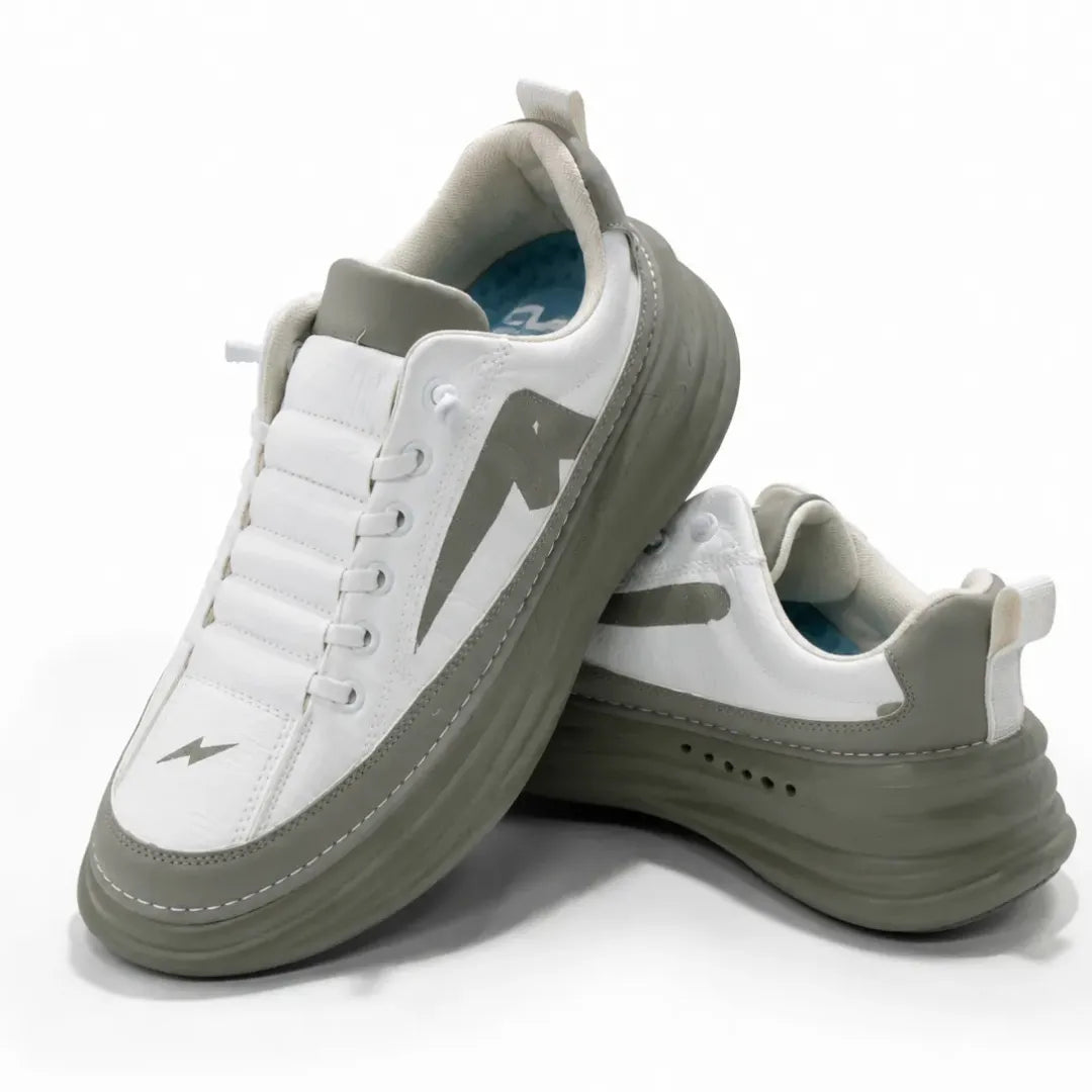 A pair of chunky platform sneakers in white and olive green, featuring a thick sole, white laces, and a stylized side logo, set against a plain white background.