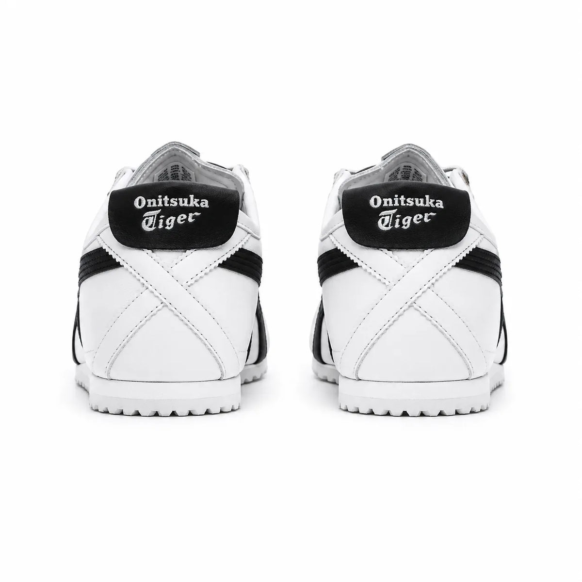 A pair of white and black Onitsuka Tiger sneakers shown from the back, featuring the brand name in white gothic lettering on black heel tabs.