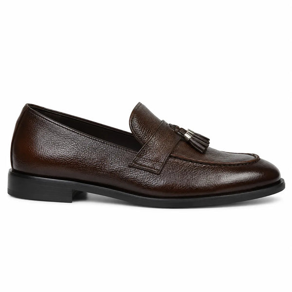 A single dark brown leather loafer with a pebbled texture, featuring a decorative strap with a tassel detail and a low black heel