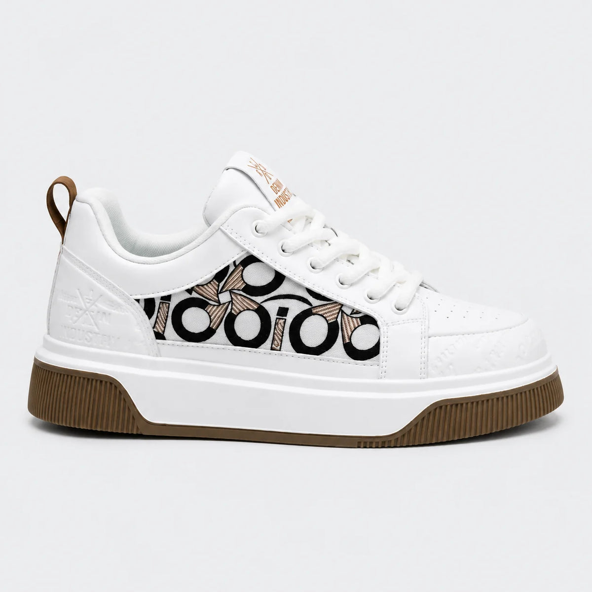 A white low-top sneaker with a brown and black monogram pattern on the side, white laces, and a brown rubber sole, shown against a light gray background.